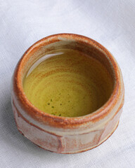 Japanese tea Genmaicha. Ceramic glass. White fabric background.