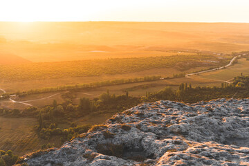View from the height of the white rock and green valley in sunset orange lights. Blue sky, a small...