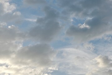 Light blue sky with light gray and white clouds in diffused light