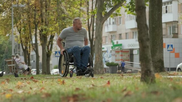 Handicapped man in wheelchair walk at the park alley