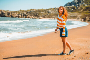 Beautiful young woman with long hair walks along the Black sea on the beach