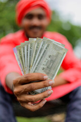Young indian farmer counting and showing money