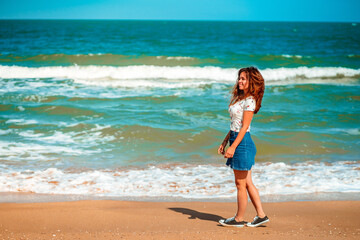 Fototapeta premium Beautiful young woman with long hair walks along the Black sea on the beach