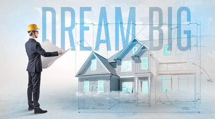 Young engineer holding blueprint with DREAM BIG inscription, house planning concept