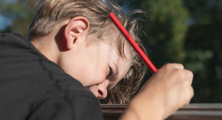 Fototapeta premium A little boy draws with a pencil
