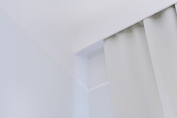 Interior details close up. White wall, ceiling, cornice niche, curtains on the window