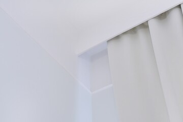 Fototapeta premium Interior details close up. White wall, ceiling, cornice niche, curtains on the window