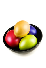 Fototapeta na wymiar Group of colored Easter Eggs in saucer on white background. A bunch of pearl colored easter eggs in black saucer isolated on white with shadow. Studio shot.