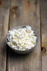 Selective focus. Fresh cottage cheese in an iron bowl. Rustic style.