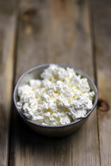 Selective focus. Fresh cottage cheese in an iron bowl. Rustic style.