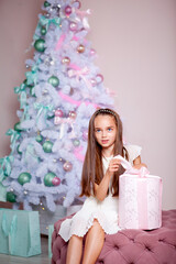 cute girl in a room decorated for christmas holding a christmas present