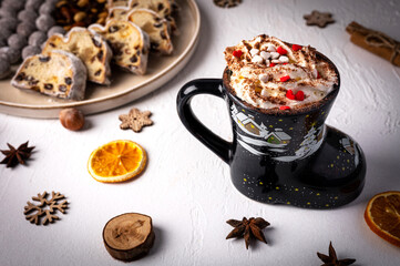Winter hot drink in funny cup, cacao with Christmas stollen on wooden board with dried fruits and nuts. Traditional german cake.Concept for postcard, holiday greeting.