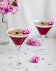 Pink drinks with pink flowers on light background.