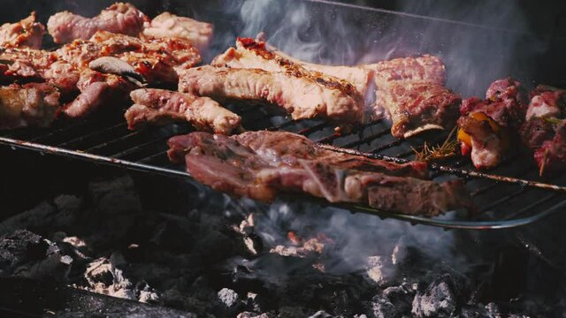 Grill the meat on the grill. Rest and lunch in the garden. Smoke from the coals. Pieces of meat and lard close-up.Flips to the other side.