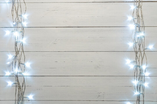 Christmas Background With Garland Lights On Natural White Wood Boards Backdrop. Copy Space.