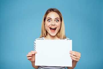 Fototapeta premium Emotional woman holding a sheet of paper in her hands lifestyle close-up blue background Copy Space