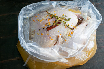 Brining a turkey in a plastic bag: A raw turkey in bourbon brine with rosemary, cinnamon sticks,...