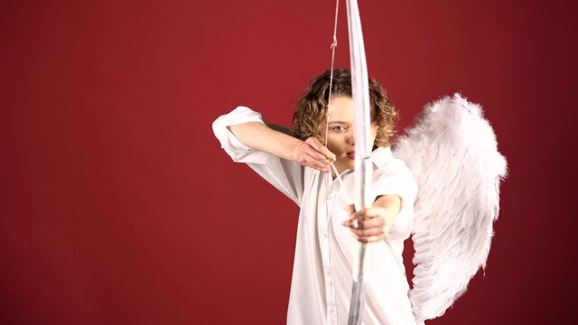 Woman as cupid angel aiming with wings, bow and arrow. Valentine's Day. Valentine female.