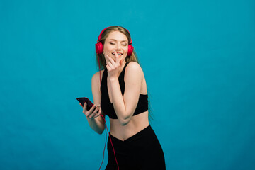 Fit young woman with headphones smiling after workout. Female athlete resting at training session.