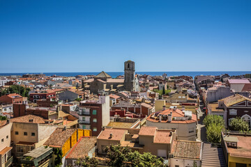 View over the roofs of old town Malgrat de Mar (Spain) from the hill with Mediterranean sea in the background and the Cathedral of the Coast in the middle