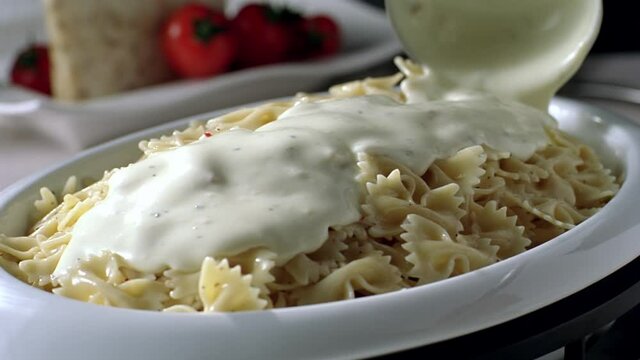 The Sauce Is Poured Over The Pasta On The Serving Plate In Slow Motion. Yogurt Sauce Pouring Into The Pasta.