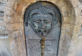 Antica fontanella con bassorilievo volto in bronzo su antiche mura chiesa