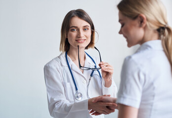 beautiful woman doctor with stethoscope shaking hands with female patient