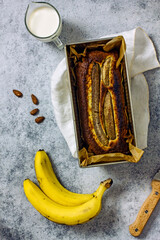 Homemade Vegan Gluten Free Banana Bread Sugar Free. Oatmeal bread with banana, honey and nuts in a baking dish on a gray table surrounded by ingredients. Top view, flat lay. Healthy sweets concept