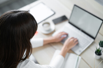 Close-up female head. Business woman types on laptop.