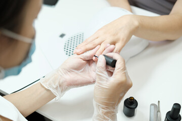 manicurist applying moisturising oil on finger nails for anti age nail care. rejuvenating and fortifying treatment in beauty salon. beautyful hands. professional care.