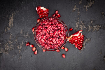 Fresh made preserved Pomegranate seeds on a slate slab (close-up shot; selective focus)