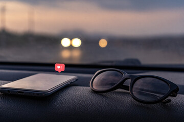 Cell phones and lenses on the car panel on the road. Social media interactions on mobile phone with...
