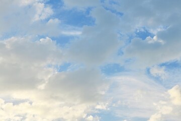Light blue sky with light gray and white clouds in diffused light