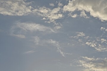 Light blue sky with light gray and white clouds in diffused light