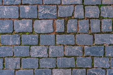 Cobblestone road for background and texture. Old road made of granite paving stones.