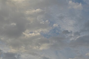 Light blue sky with light gray and white clouds in diffused light