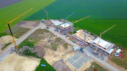 Neubaugebiet am Stadtrand mit vielen Häusern in Bau und Baukränen neben landwirtschaftlich...