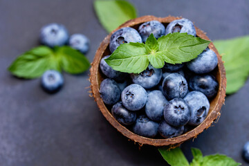 Freshly picked blueberries in coconut bowl on dark background. Healthy organic seasonal fruit background. Berries closeup