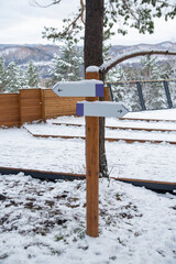 Wooden post with direction signs on a forest road in winter.