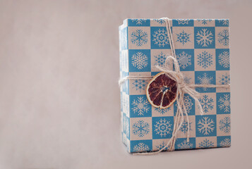 Packed box with a new year's gift. decoration in the form of a string with dried orange. light background.