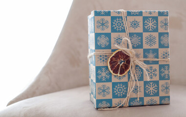 new year's blue and white box with a gift on a light background. rope with an orange as a decoration.