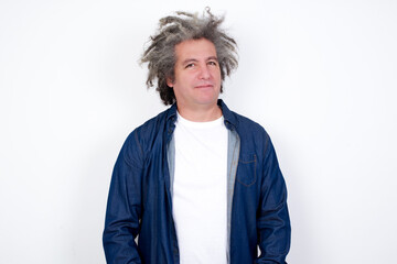 Handsome mature caucasian man with afro grey hair standing over white background looking at camera with charming cute smile.