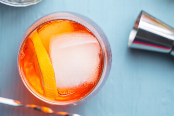 Glass of classic italian aperitif spritz cocktail with slice of orange as garnish on a blue table. Top view