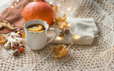 Obraz na płótnie Canvas Cup of warm tea fall style, fall scene with leaves, lights and acorns, cozy autumn aesthetic concept