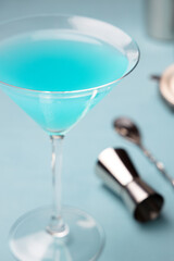 Cyan cocktail, martini glass and some bartender accessories on a blue table