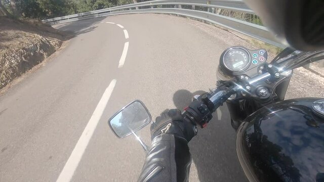 Riding an old vintage black motorbike on a winding asphalt road with shining handlebar rider point of view