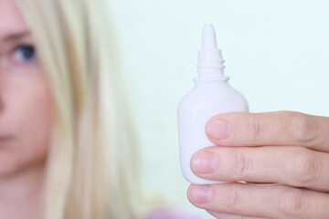 A bottle of nasal spray in a hand of a woman close up, allergy, viral and bacterial rhinitis and sinusitis treatment