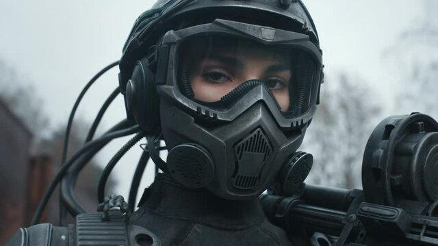Portrait female future soldier in fiction helmet after nuclear war. Lonely star trooper cyborg girl in futuristic combat suit with assault gun. Cyberpunk military post apocalypse concept