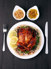 Homemade chicken rotisserie with thyme, lemon close up on a slate board on the table. 