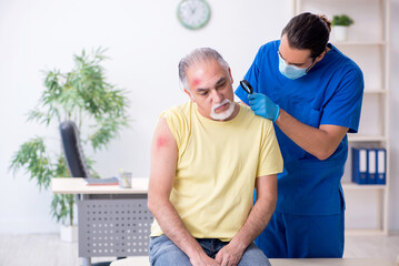 Obraz premium Injured old man visiting young male doctor traumatologist